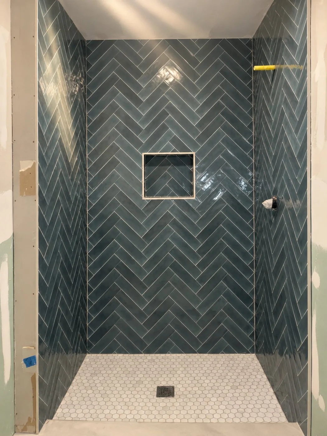 Blue herringbone tile shower with niche and white hexagon floor